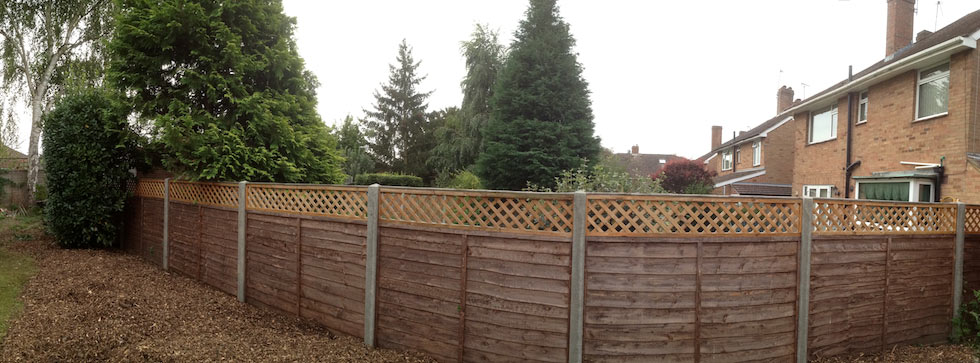 Five-foot lap panelling with decorative trellis top and concrete posts.